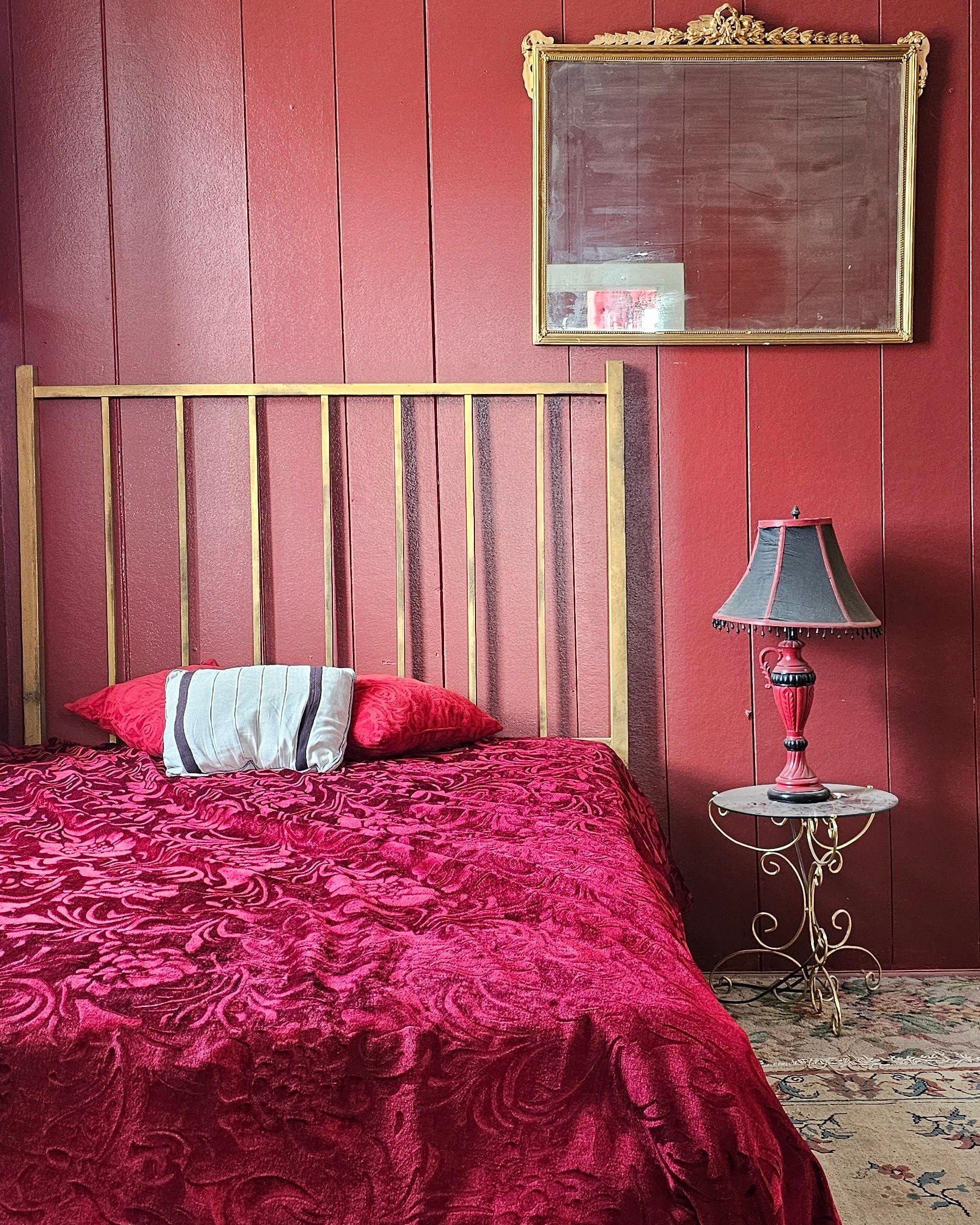 A parlor room at the Dumas: brass bed, red damask spread, gilt mirror